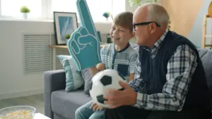 Un grand-père et son petit-fils regardent un match de football à la télévision.