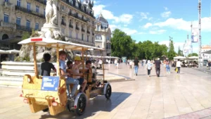 Un groupe d'enfants s'amuse dans une rosalie en bois sur la place de la Comédie.