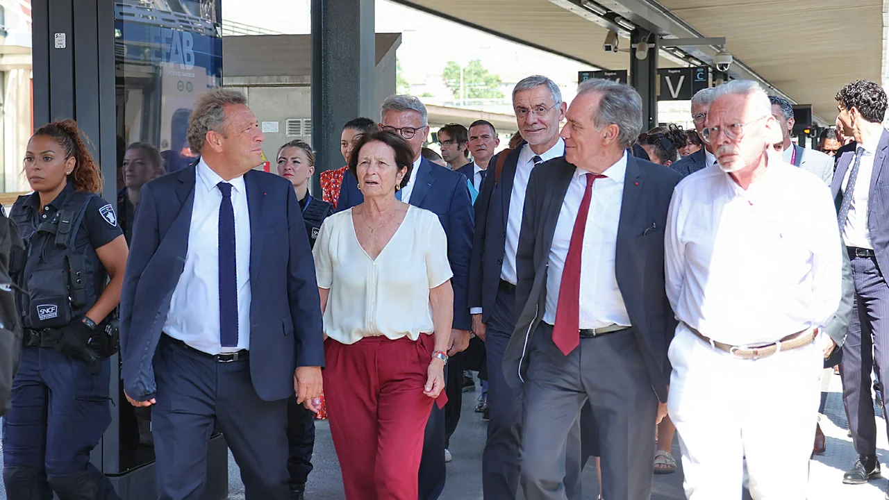 Un groupe de personnalités politiques marchant sur le quai d'une gare ferroviaire en France.