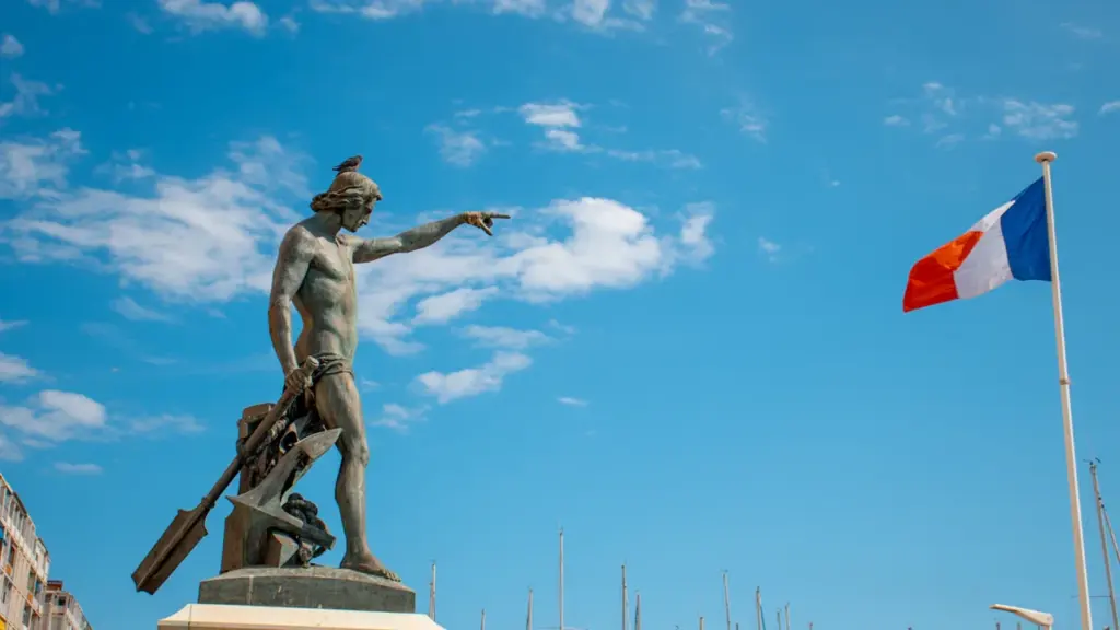 Statue historique au port de Toulon avec le drapeau français flottant fièrement.