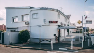 Façade d'un bâtiment blanc typique avec une enseigne Tabac en plein jour.