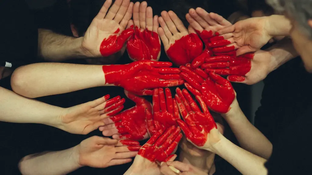 Plusieurs mains peintes en rouge formées ensemble pour symboliser le don du sang.