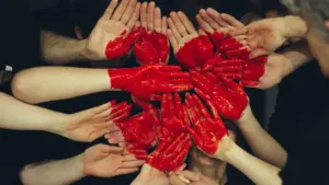 Plusieurs mains peintes en rouge formées ensemble pour symboliser le don du sang.