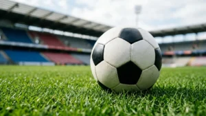 Un ballon de football classique posé sur l'herbe verte d'un grand stade vide.