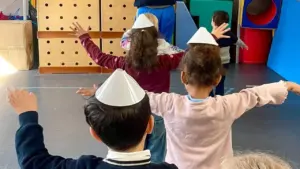 Un enseignant et des jeunes enfants avec des cônes en papier sur la tête.