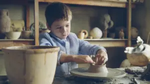 Un jeune étudiant concentré façonne de l'argile sur un tour de potier traditionnel.