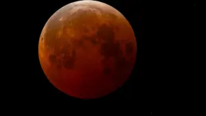Une éclipse lunaire totale montrant une lueur rougeâtre captivante dans le ciel nocturne sombre.