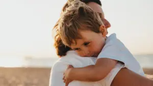 Une mère serre affectueusement son jeune enfant dans ses bras au bord de la plage.
