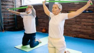 Un homme et une femme seniors s'entraînant avec des bandes élastiques dans une salle sportive.