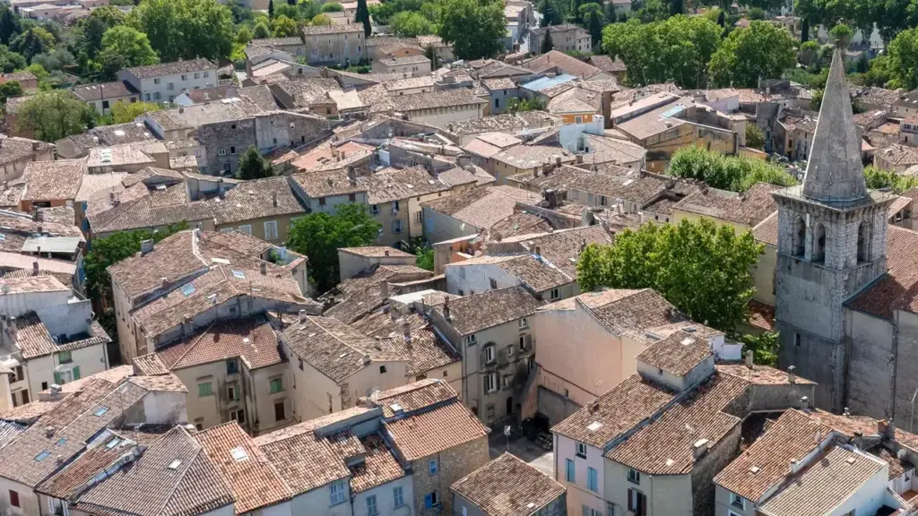 Vue aérienne d'un village provençal typique avec des maisons aux toits de tuiles orangées.