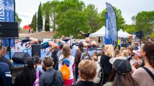 Plusieurs athlètes torse nu effectuent des figures acrobatiques sur une scène lors d'un événement sportif.