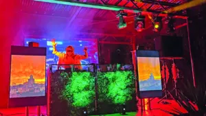 Un DJ portant une casquette mixe sur scène sous des éclairages rouges et verts vibrants.