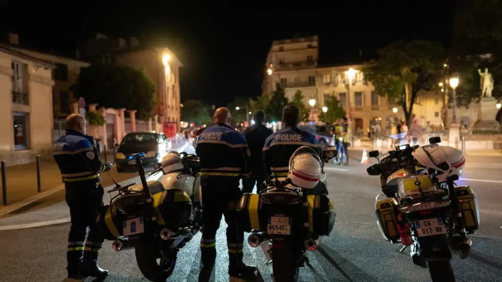Agents de police français à moto surveillant une rue sombre lors d'une patrouille nocturne.