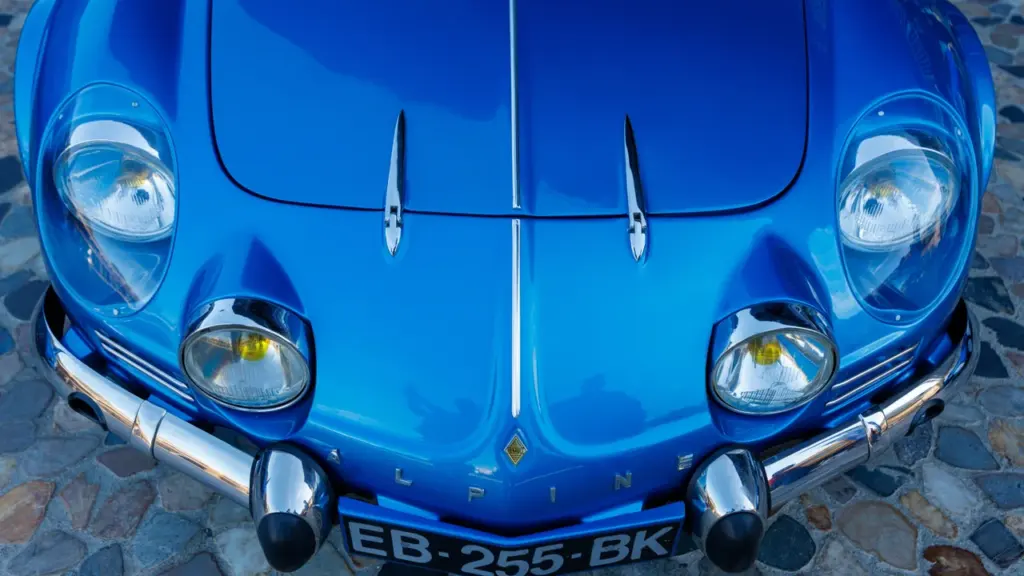 Gros plan sur l'avant d'une voiture Alpine bleue vintage avec quatre phares ronds brillants.