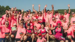 Un grand groupe de coureurs souriants en t-shirts roses posant ensemble pour une photo.