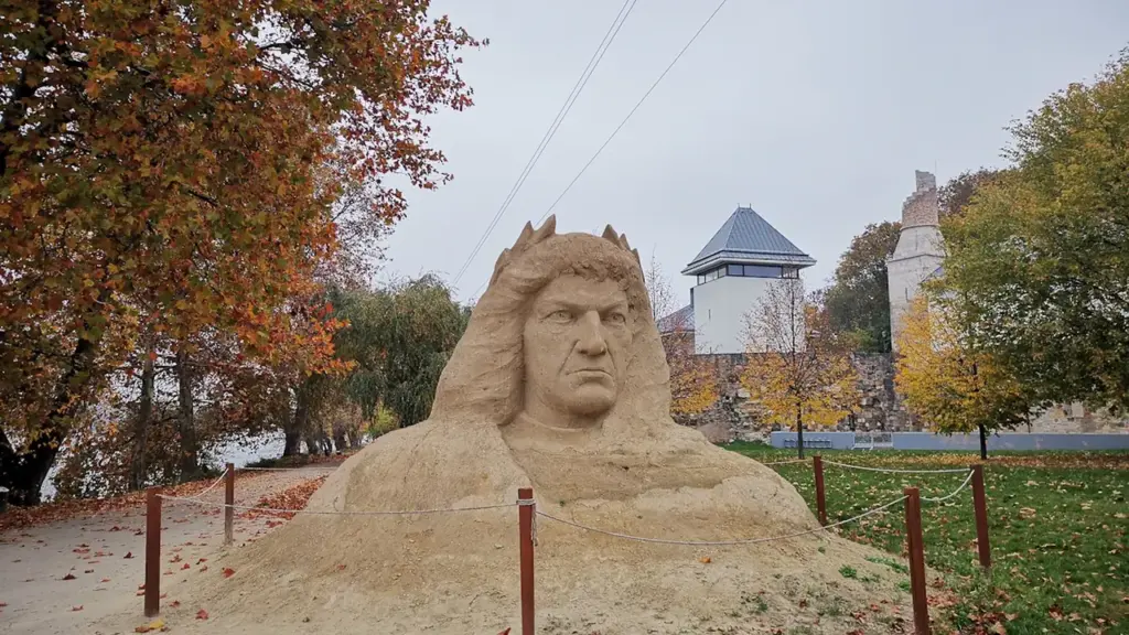 Une grande sculpture en sable représentant un visage historique dans un parc urbain français.