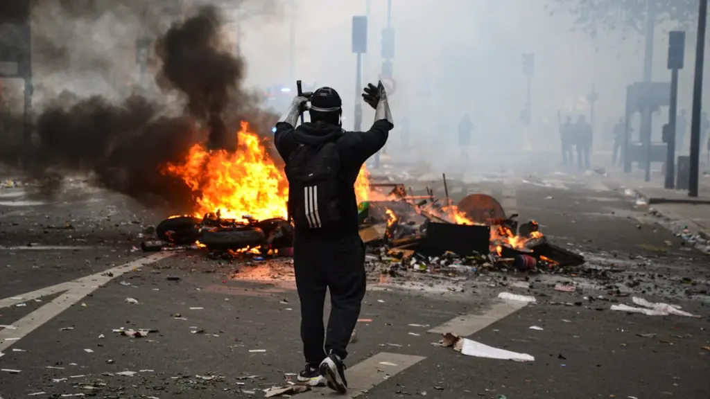 Un manifestant face à une barricade enflammée en plein centre-ville lors d'une manifestation.